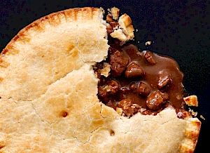 Photograph of whole meat pie with a slice taken out