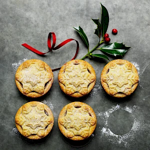Photograph of two rows of mince pies with holly and ribbon