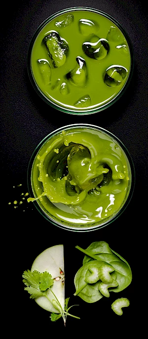 Photograph of glasses of apple, spinach and celery juice with an ice cube splash