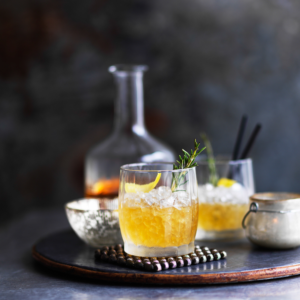 hotograph of a whiskey cocktails with rosemary and lemon, decanter