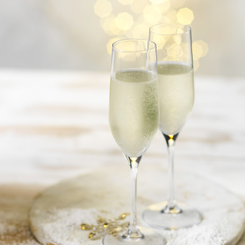 Photograph of champagne flutes of cava with Christmas fairy lights