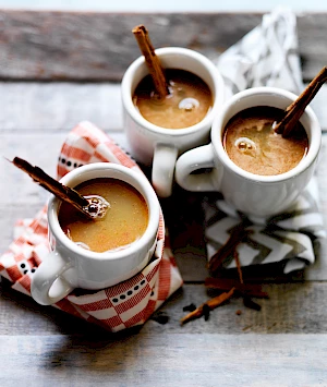 Photograph of hot spiced apple drink with cinnamon sticks stirrers